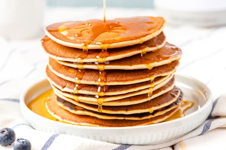 Maple syrup being poured over pancakes