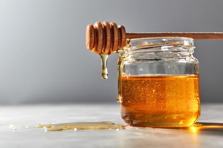 A jar of honey with a honey dipper