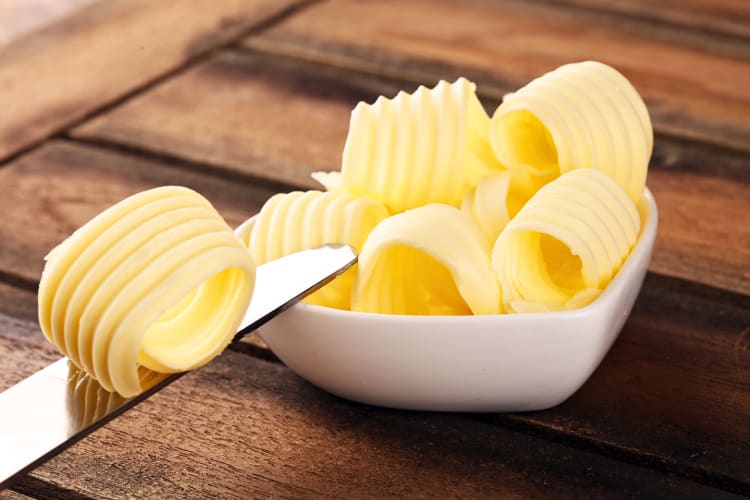 One layer of margarine on a knife next to other layers in a bowl