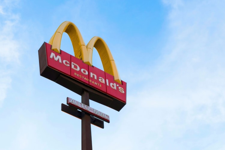 A McDonalds arches sign next to a blue sky with clouds