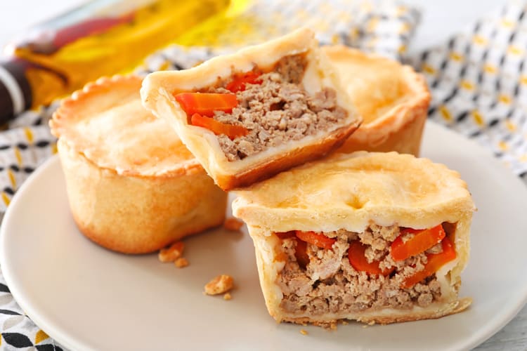 Two halves of a meat pie and two whole ones, on a plate