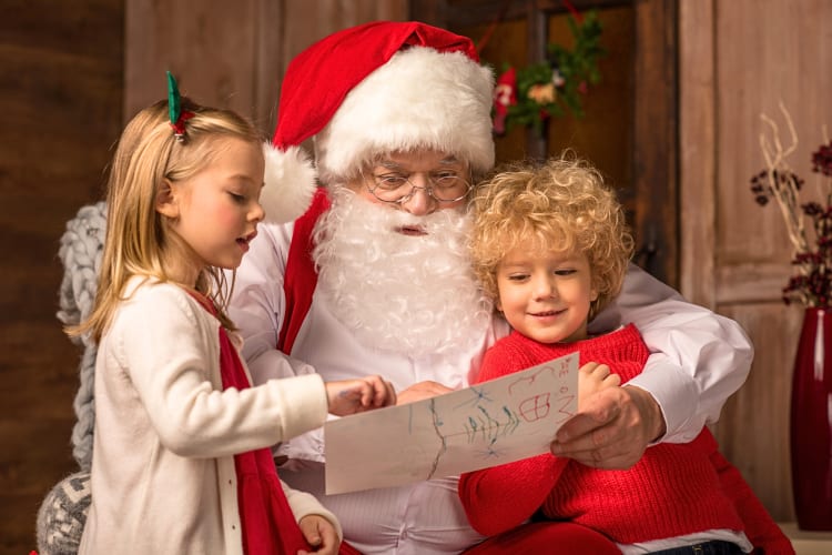 Two children sitting with and chatting to Santa as a family Christmas tradition