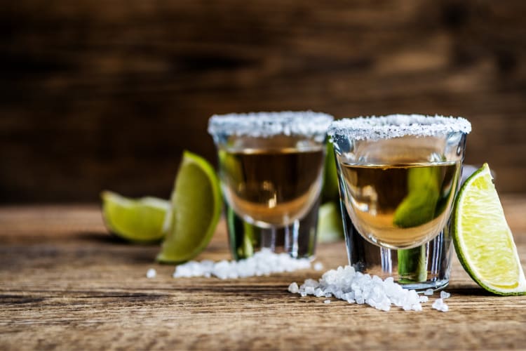 Shots of tequila next to lime slices