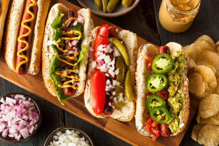Four hot dogs, each with an assortment of different toppings on top