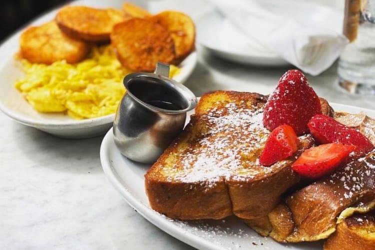 French toast with strawberries on a table next to another dish