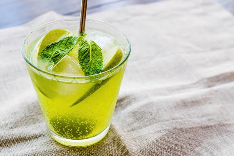 Green cocktail garnished with basil leaves