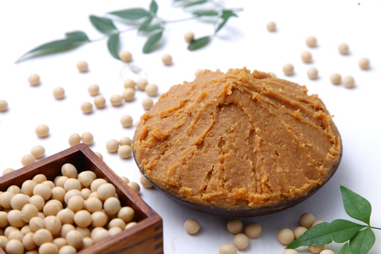 Miso paste in a bowl next to soybeans