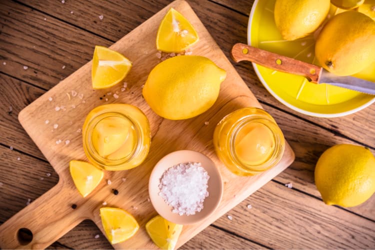 Fresh and preserved lemons on a wooden cutting board