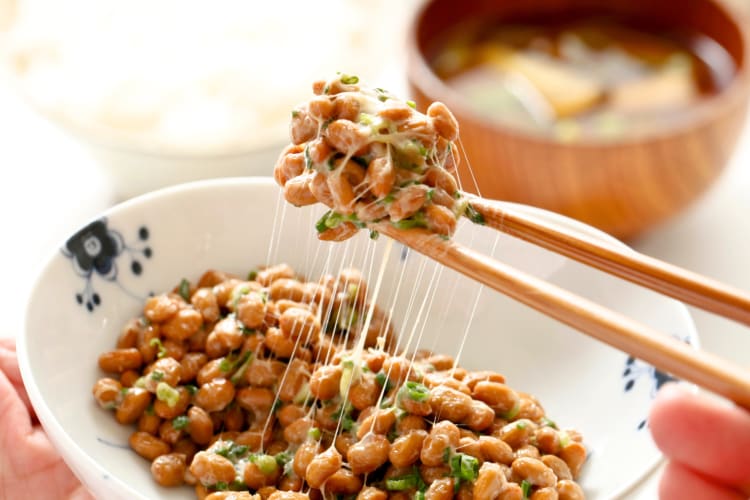 Chopsticks picking up fermented soybean natto