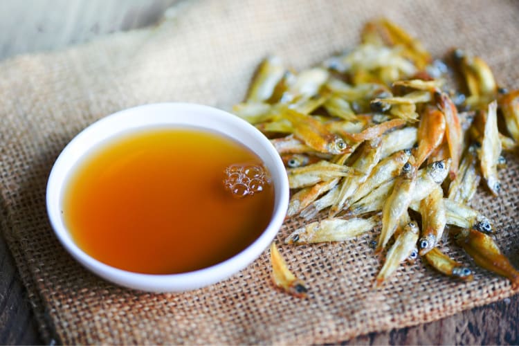 A bowl of fish sauce next to small dried fish