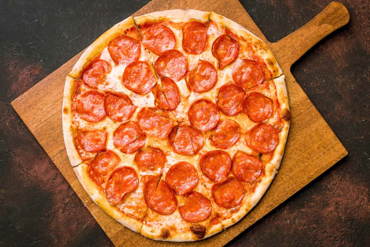 Aerial view of a pepperoni pizza on a wooden serving board