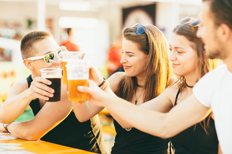 Four people raising their beer cups in a toasting motion at a beer festival