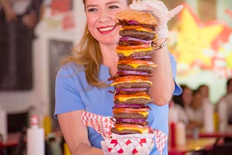 A women holding a burger with multiple patties