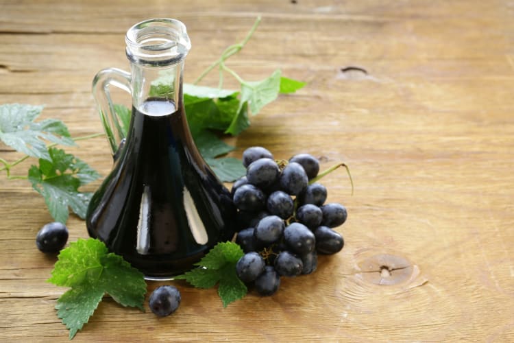 A jug of balsamic vinegar next to grapes