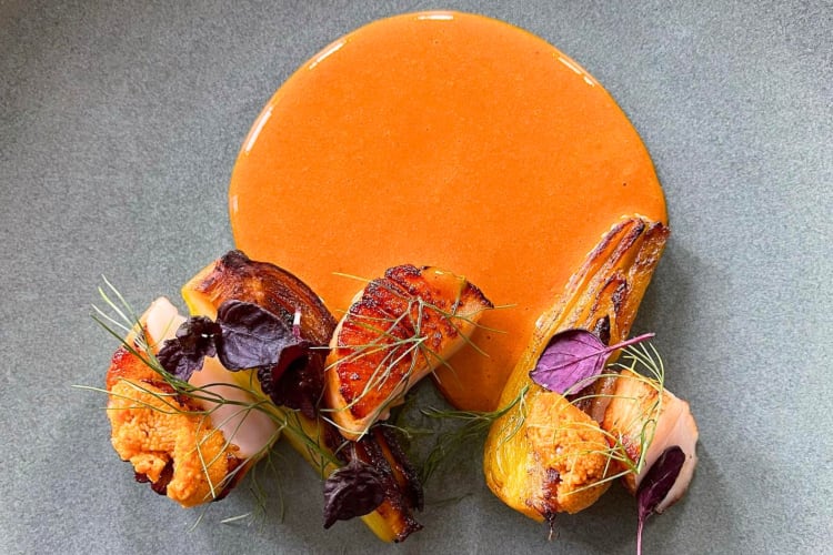 A high-end dish with orange sauce on a grey plate