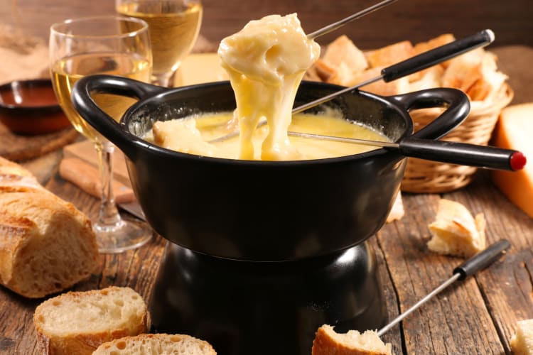 A fondue pot surrounded by bread and wine glasses