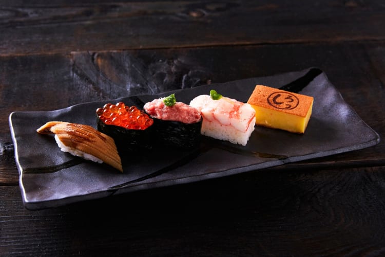 A selection of nigiri on a black plate 