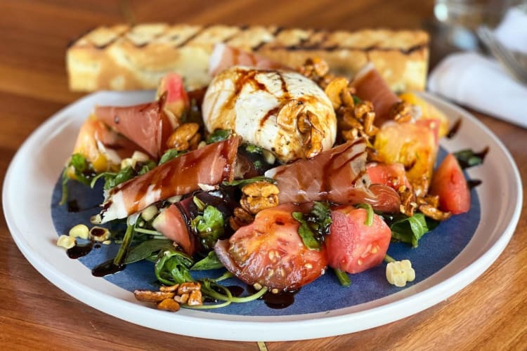 A burrata salad on a blue and white plate 