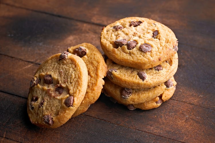 Six chocolate chip cookies on a wooden surface