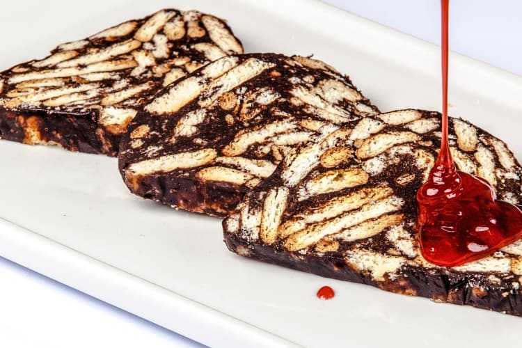 Three slices of mozaik pasta — a Turkish cake, with syrup being poured over one slice