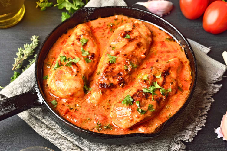 Three chicken breasts in a pan covered with sauce