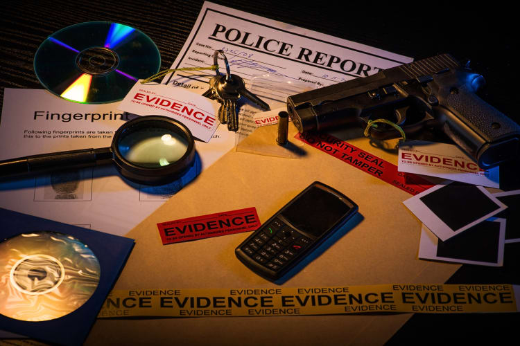 Police desk with a gun, cellphone, magnifying glass, keys and reports as evidence