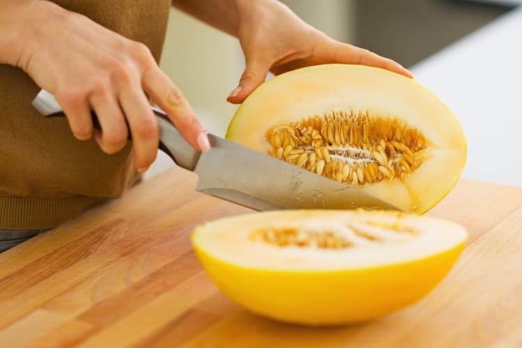 A person cutting a muskmelon