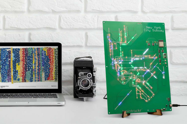 A circuit board next to a laptop and a camera