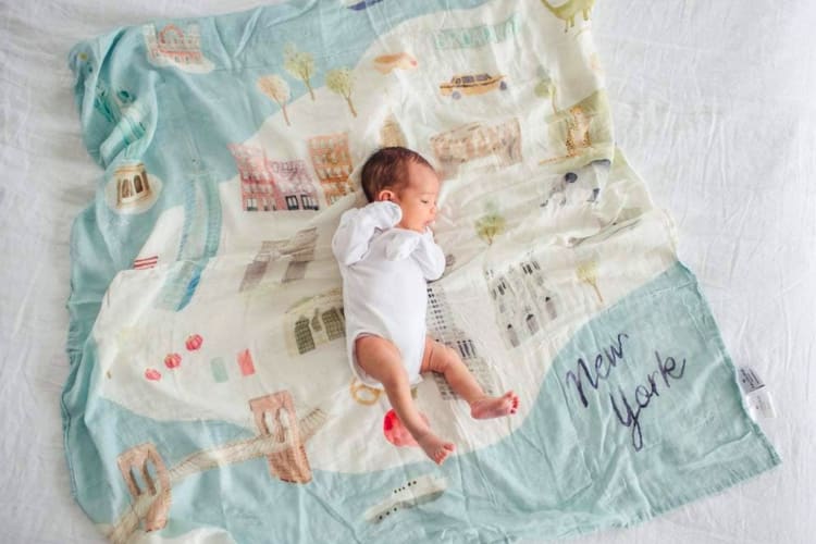 A baby lying on a New York City themed blanket