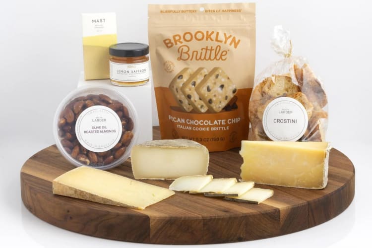 A cheese board with cheese, a bag of almonds, cookies and other food items