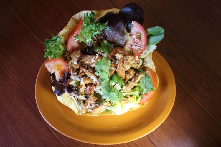 Grilled chicken breast served on a bed of mixed greens with jack cheese, garnished with black olives and diced tomatoes.