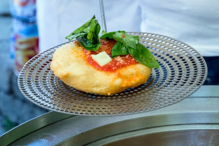 A fried pizza with tomato sauce and basil