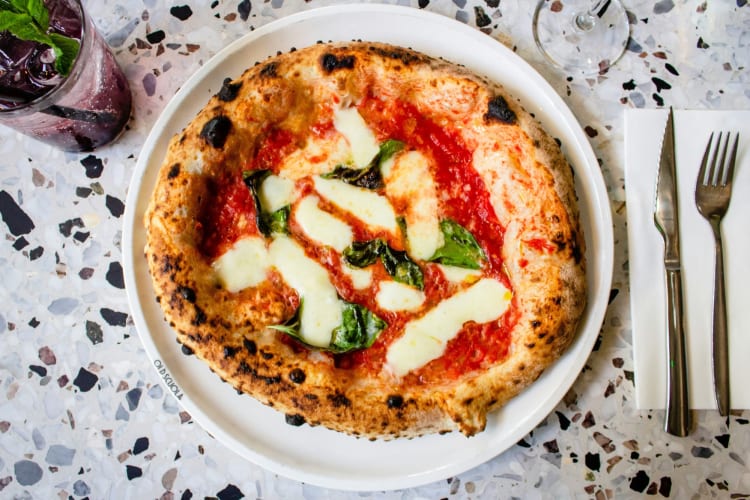 A pizza with tomato sauce and melted mozzarella, topped with basil
