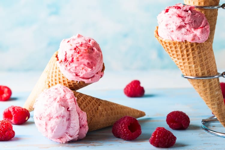 Raspberry ice cream in cones next to fresh ice cream