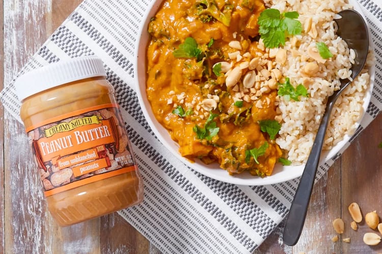 A jar of peanut butter next to a peanut curry with rice
