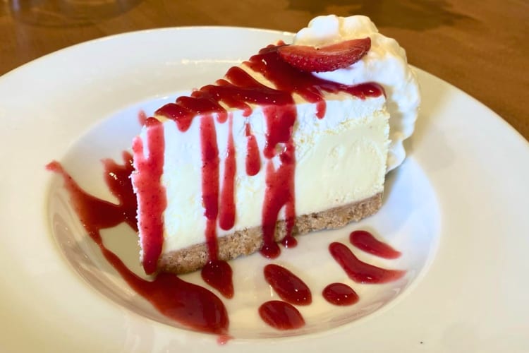 A piece of cheesecake with strawberry sauce on a plate