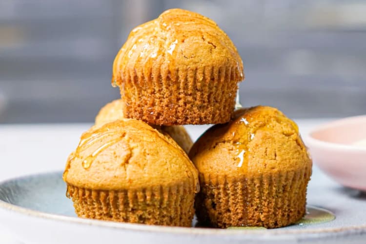 Four cornbread muffins stacked on a plate
