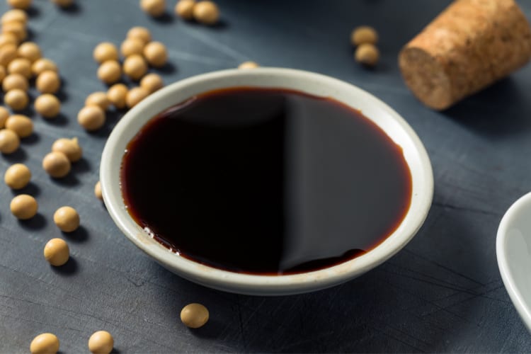 A bowl of tamari on a black surface