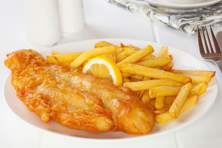 Fish and chips on a plate with a lemon slice in the middle