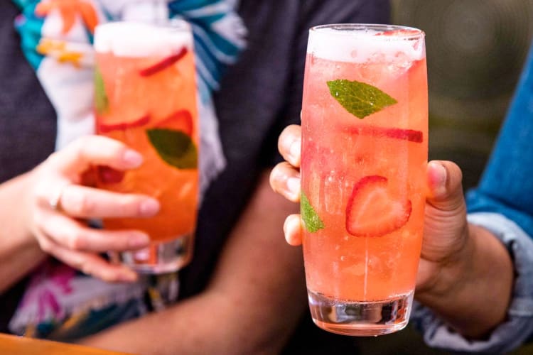 Two people holding strawberry and mint drinks