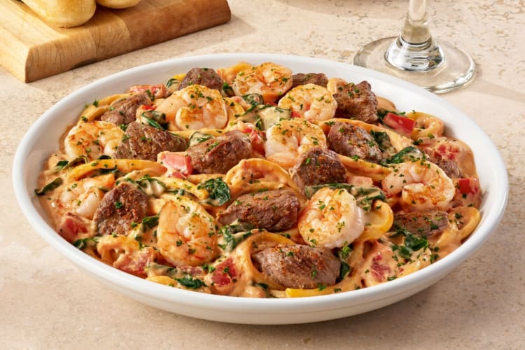 A bowl of pasta with shrimp and steak