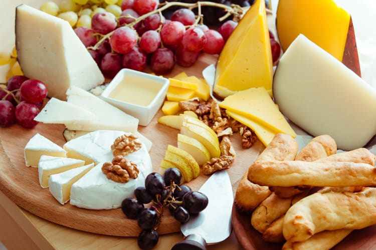 Cheese board with a variety of cheeses and fruit, added to bread, sauce and walnuts