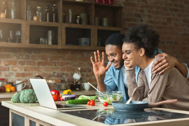 Couple smiling at their laptop during an online cooking class