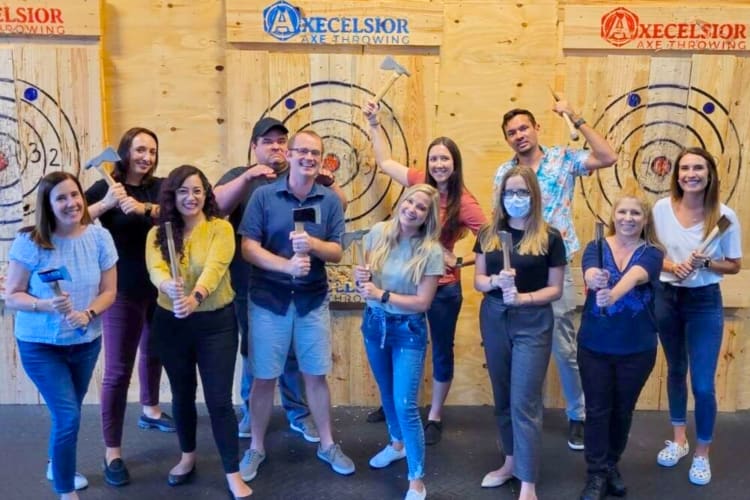 A group posing for a photo at an axe throwing venue