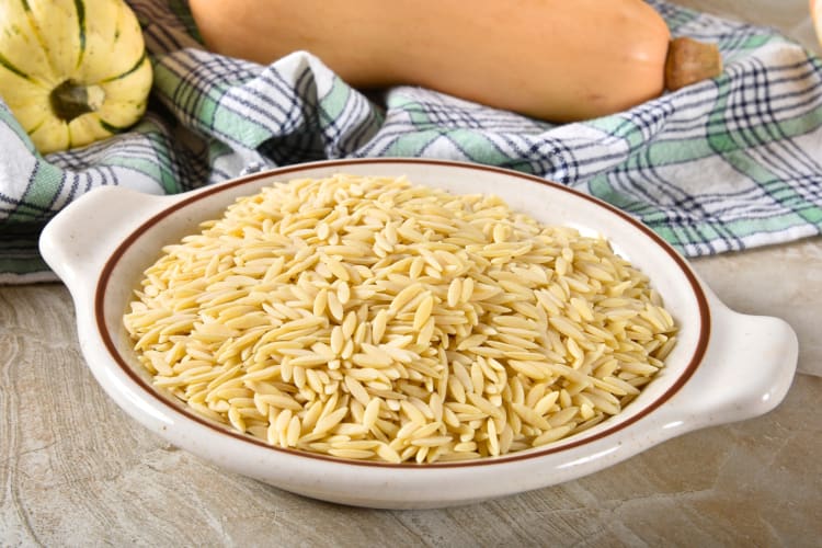 A dish with dried orzo next to a cloth