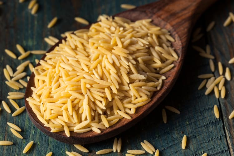 A wooden spoon with dried orzo