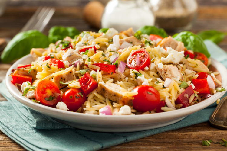 An orzo dish with tomatoes, red onion and chicken