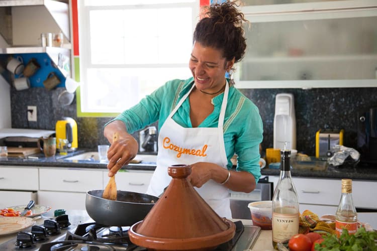 Person with a Cozymeal apron cooking in a kitchen