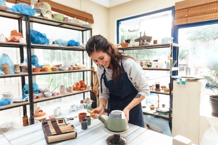 Teenage girl painting a ceramic bowl as a teen birthday party idea