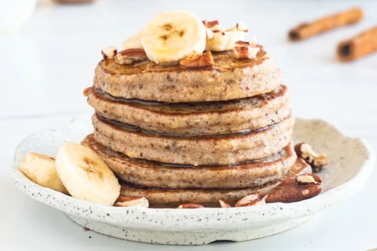A stack of pancakes topped with bananas